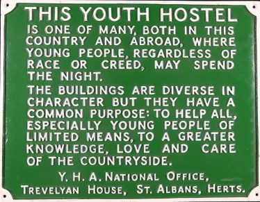 Rectangular green and white cast iron sign stating objectives of the Youth Hostel Association and common aim 